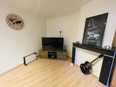 a living room with a tv and a fireplace and a clock at Heart of Antwerp in Antwerp