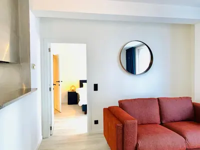 a living room with a red couch and a mirror at Belfort Shortstay in Ghent