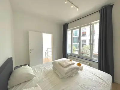 a bedroom with a white bed and a large window at Belfort Shortstay in Ghent