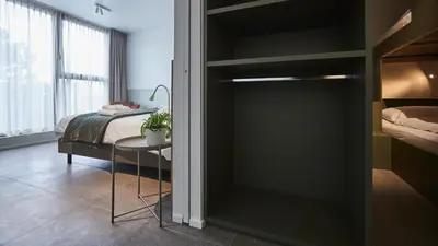a bedroom with a bed and a glass door with a table at Het Kasterhuis in Wetteren