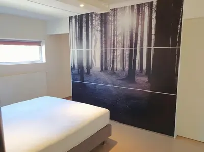 a bedroom with a bed and a painting of a forest at Portus Ganda in Ghent