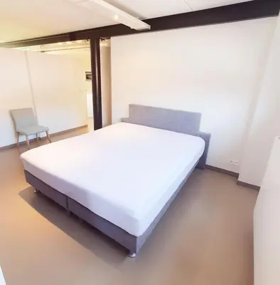 a bedroom with a large white bed and a chair at Portus Ganda in Ghent