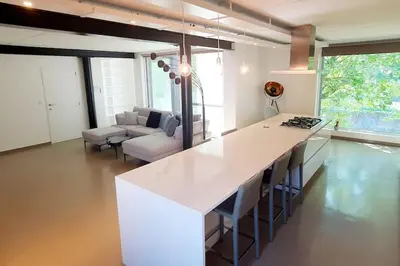 a kitchen with a white counter and a living room at Portus Ganda in Ghent