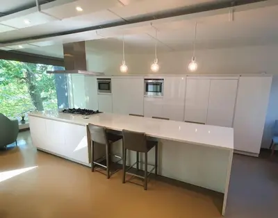 a kitchen with a large white counter and stools at Portus Ganda in Ghent