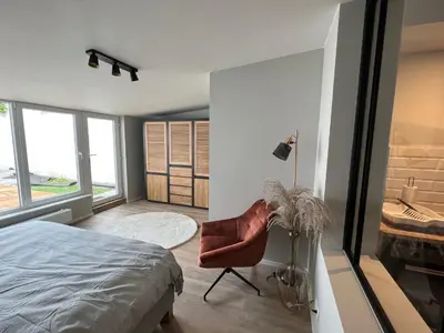 a bedroom with a bed and a chair and windows at Appartement Martine in Brussels