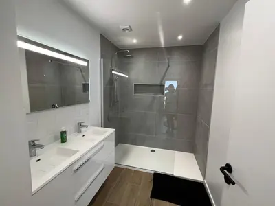 a white bathroom with a shower and a sink at Appartement Martine in Brussels