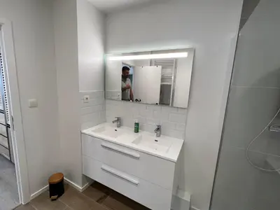 a woman taking a picture of a bathroom with a sink at Appartement Martine in Brussels
