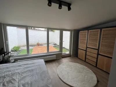 a bedroom with a bed and a large window at Appartement Martine in Brussels