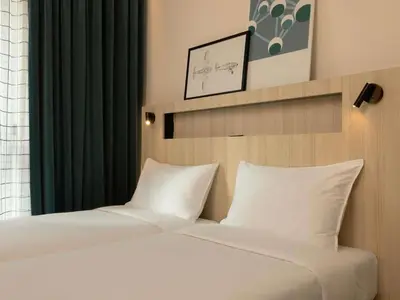 two beds in a hotel room with green curtains at Aparthotel Adagio Access Brussels Airport in Machelen