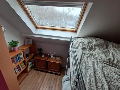 a attic bedroom with a bed and a window at Maison d'hôte in Grez-Doiceau