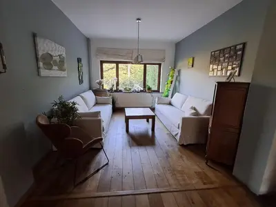 a living room with a white couch and a table at Maison d'hôte in Grez-Doiceau