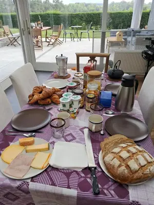 a table with cheese and bread on a purple table cloth at Maison d'hôte in Grez-Doiceau