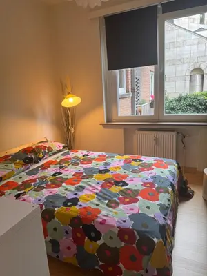 a bedroom with a bed with a colorful comforter and a window at Luxe Serene Residence in Brussels