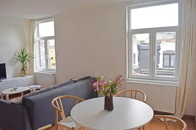 a living room with a couch and a table with flowers at Astrid Sauna Appartement Antwerp in Antwerp