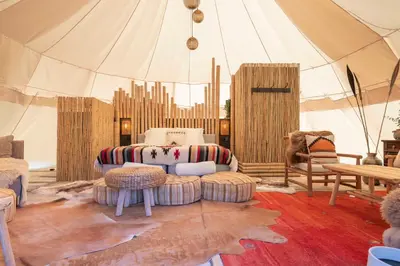 a room with a tent with a couch and chairs at Tipi Bo Deluxe in Kaprijke