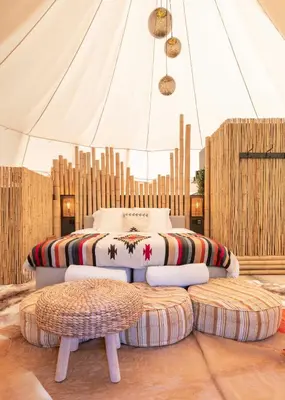 a bedroom with a bed and two ottomans at Tipi Bo Deluxe in Kaprijke