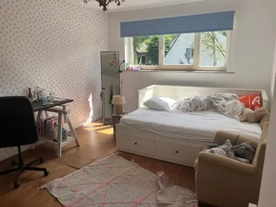 a bedroom with a bed and a desk and a window at Zonnebos in Kraainem