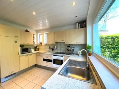 a kitchen with a sink and a large window at Zonnebos in Kraainem