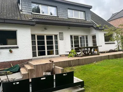 a house with a wooden deck in the yard at Zonnebos in Kraainem