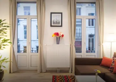 a living room with a couch and a vase of flowers at Central Brussel - steps Grand Place - local vibrant neighbourhood in Brussels