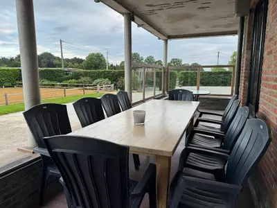 a wooden table and chairs on a patio at Welkomhoeve in Grobbendonk