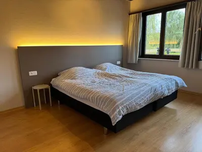 a bedroom with a bed with a blue comforter and a window at Welkomhoeve in Grobbendonk