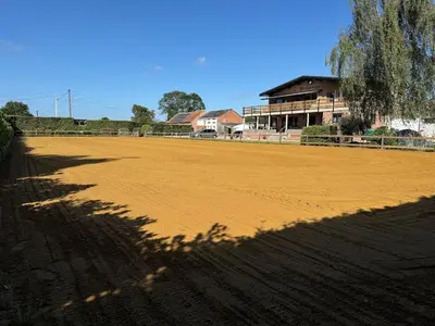 a large dirt field with a building in the background at Welkomhoeve in Grobbendonk