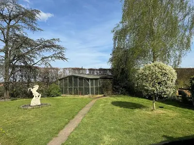 a garden with a statue and a glass house at Welkomhoeve in Grobbendonk