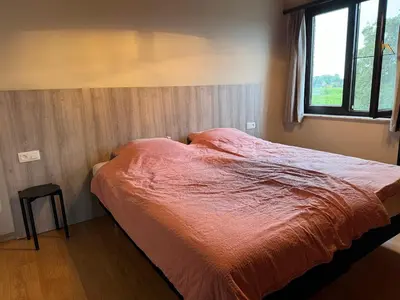 a bed with an orange comforter in a bedroom at Welkomhoeve in Grobbendonk