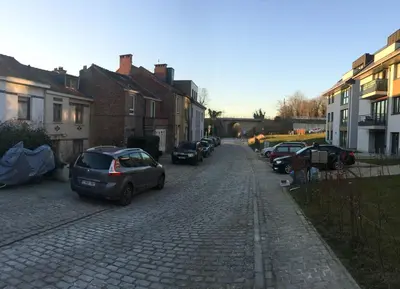a cobblestone street with parked cars and houses at B&B Moensberg in Brussels