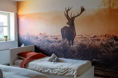 a bedroom with a painting of a deer on the wall at Doornhof, rustig gelegen vakantiehuis in Haaltert