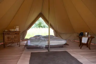 a tent with a bed and a table in it at Rosephine Glamping in Lievegem