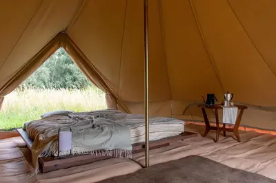 a bed in a canvas tent with a table at Rosephine Glamping in Lievegem