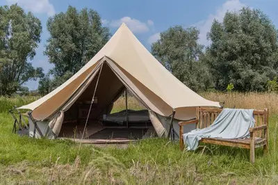 a canvas tent with two chairs in a field at Rosephine Glamping in Lievegem