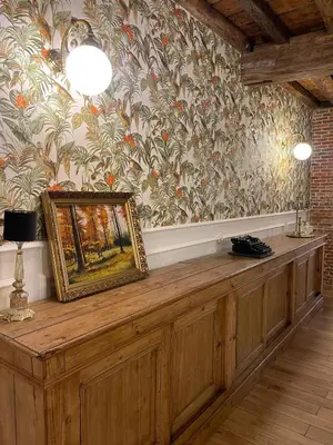 a painting on a wooden counter in a room with wallpaper at La Petite Foret Art Deco Apartment in Brussels in Brussels