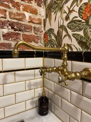 a bathroom sink with a gold faucet on a wall at La Petite Foret Art Deco Apartment in Brussels in Brussels