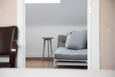 a gray couch in a living room with a stool at Restaurant & Guesthouse Cachet de Cire in Turnhout