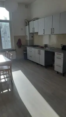 a kitchen with white cabinets and a table and chairs at Appartement cozy à Saint-Gilles in Brussels