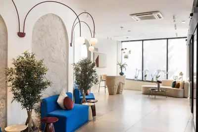 a lobby with blue chairs and potted plants at The Liman Hotel in Brussels