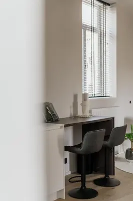 a desk with two chairs in a room with a window at Mooi licht appartement in bruisend Antwerpen! in Antwerp
