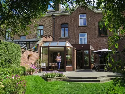 a woman standing in front of a house at B&B Woluwé in Brussels