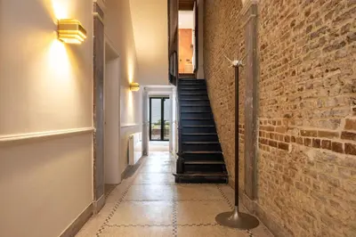 a hallway with a brick wall and a staircase at Jardin du Béguinage - Peaceful Luxury Home in Brussels in Brussels