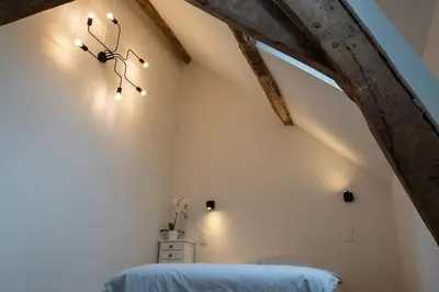 a clock on the wall of a room with a bed at Square Shaped Farmhouse from 1713 in Nieuwenhove