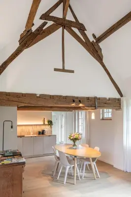a kitchen and dining room with a wooden table and chairs at Boonackere Cottage in Oosterzele