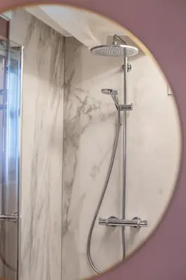 a shower in a bathroom with a round mirror at Boonackere Cottage in Oosterzele