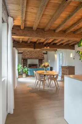 a dining room with a table and a fireplace at Boonackere Cottage in Oosterzele
