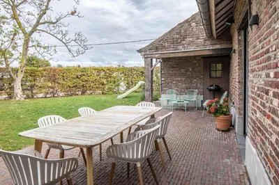 a wooden table and chairs on a brick patio at Boonackere Cottage in Oosterzele