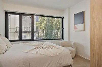 a bedroom with a bed and a chair and a large window at Deluxe 2-BR Apartment in Antwerp in Antwerp