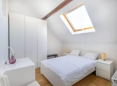 a white bedroom with a bed and a skylight at Élégance Cinquantenaire in Brussels