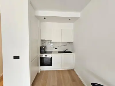 a white kitchen with white cabinets and a stove at Centre de Bruxelles Merveilleux ! in Brussels
